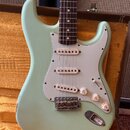 Světle zelená elektrická kytara typu Stratocaster s bílým pickguardem a hnedým hmatníkem. Tělo vykazuje početné praskliny laku (crackle finish) a dro…