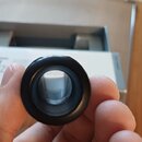 Fotografie zachycuje detail černé, kulaté součástky z plastu nebo gumy s prázdným středem. Předmět je držen v lidské dlani. Na součástce nejsou vidit…