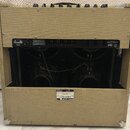 Zadní strana kytarového komba s béžovým potahem z textilie. V horní části je černý kovový panel s nápisy CAUTION!, 230V~50Hz, 100-240V~50/60Hz a text…