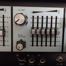 Detailní pohled na ovládací panel míchacího pultu s posuvníky a otočnými knoflíky. Na panelu jsou viditelné nápisy VOLUME a ECHO REVERB u ovládacích…