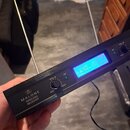 Černý bezdrátový přijímač s nápisem MALONE WIRELESS RECEIVER a doprovodným logem. Zařízení má modrý digitální displej s hodnotami 176.400... a 203.40…
