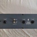 Záběr na zadní panel šedého elektronického zařízení. Jsou zde vidět dva konektory XLR s nápisy BAL / UNBAL INPUT a jeden konektor XLR s nápisem BAL /…