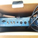 Zadní panel modrého zařízení s nápisem Roland GR-55 GUITAR SYNTHESIZER. Jsou zde vidět různé konektory, včetně vstupů GK IN, GUITAR OUT, OUTPUT R a L…