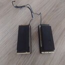 Dvě obdélníkové piezoelektrické snímače s černým povrchem a kovovým rámem. Z obou komponent vycházejí tenké šedé vodiče, které jsou v horní části odh…