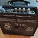 Zadní strana černého kytarového komba s označením MODEL: HT-1R. Na horní části jsou čtyři kovové oválné knoflíky s nápisy GAIN, VOLUME, EQ a REVERB,…
