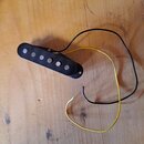 Černý elektrický snímač typu humbucker s šesti viditelnými kovovými póly. Ze snímače vedou dva volné vodiče, jeden žlutý a jeden černý. Předmět leží…