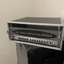 Černý basový zesilovač s nápisem GK GALLIEN-KRUEGER a označením modelu 2001RB, umístěný v transportním flightcasu s hliníkovými hranami. Přední panel…