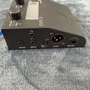 Černý elektronický přístroj s nápisem OPUS na horní části. Na předním panelu jsou dva černé oválné ovladače, displej a tlačítka s nápisy PERFORM a ME…
