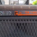 Černý výkonový zesilovač s nápisy the t.amp TA 1400 MKII a the professional power amplifier. V horní části je text FULL SYMMETRY DUAL DIFFERENTIAL HI…