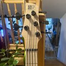 Detail hmatníku a hlavy basové kytary z přírodního světlého dřeva. Na hlavě je černý nápis SDGR a pod ním menší text SOUNDGEAR BY IBANEZ. Nástroj má…