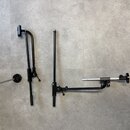 Na šedém podkladu leží tři černé kovové části mikrofonních stativů nebo ramen. Jedna část obsahuje rameno s kloubem a držákem, druhá je tvořena rozta…