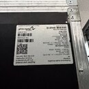 Fotografie zachycuje detail zadní strany zařízení v kovovém kufru. Na černém štítku je uveden nápis Professional Audio Amplifier, X Series x4 a značk…