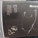 Fotografie znázorňuje krabici od mikrofonu. Na černé části obalu je bílý nápis MicroMic THE ORIGINAL, model C 520 VOCAL a texty v několika jazycích z…