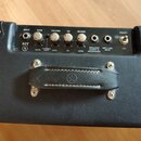 Detail zadního panelu černého kytarového komba s ovládacími prvky. Jsou zde nápisy INPUT, GAIN, VOLUME, EQ, REVERB a POWER s doprovodnými knoflíky a…