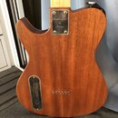Zadní strana elektrické kytary s hnědým dřevěným povrchem. Horní kovový kryt nápisu obsahuje text Handcrafted in France a sériové číslo 419101. Spodn…