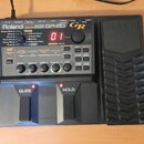 Černý kytarový syntetizátor Roland GR-20. Na předním panelu jsou vidět nápisy Roland, GUITAR SYNTHESIZER a GR-20 s červeným digitálním displejem zobr…