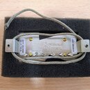 Elektrický snímač kytary v kovovém krytu, umístěný v černém pěnovém obalu. Na spodní straně jsou dvě bílé nálepky s nápisy 48879 20251008 SH-1N NECK…