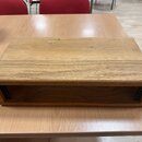 Dřevěný obal nebo stojan v hnědé barvě s viditnou strukturou dřeva. Předmět má obdélníkový tvar s otevřeným prostorem v přední části. Povrch vykazuje…