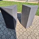 Dvě černé akustické panely z pěnového materiálu s pyramidovým povrchem na horní hraně. Panely mají hranatý tvar a jsou umístěny vedle sebe na dlažbě.…