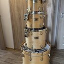Sada bubnů značky Pearl v přírodním dřevěném provedení. Na každém koruse je vidět logo Pearl s nápisem Masters Series. Bubny jsou naskládány na sebe,…