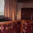 Černý kytarový kombo zesilovač s nápisem Dempsey na přední straně. Horní panel obsahuje ovládací knoflíky a přepínače. Zesilovač stojí v místnosti ve…