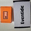 Na bílém povrchu leží dvě krabice. Menší oranžová krabice nese logo s nápisy Rainger FX a LONDON. Vedle ní je větší bílá krabice s černým nápisem Eve…