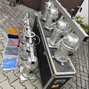 Na černém transportním kufru s kovými hranami a vedle něj stojí celkem sedm stříbrných reflektorů. K zařízení patří kovový rám a několik barevných ge…
