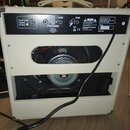 Zadní strana kytarového komba v krémové barvě s texturovaným povrchem. Na horním černém panelu jsou nápisy External Speaker Impedance 8-16 Ohms, RETU…