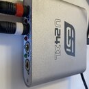 Stříbrný audio rozhraní s kovovým povrchem a logem esi a označením U24XL. Na levém boku jsou vstupy INPUT (L, R) a výstupy OUTPUT (L, R), do kterých…