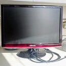 Černý počítačový monitor s červeným spodním rámem a nápisem SAMSUNG. V levém horním rohu je drobný bílý nápis SyncMaster T220. Monitor stojí na kulat…