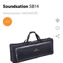 Černý klávesový obal s bílým lemováním a dvěma rukojetmi nahoře. Na přední straně je umístěno logo a nápis soundsation. Produkt je zobrazen na bílém…