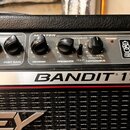Detailní pohled na ovládací panel kytarového komba s nápisem BANDIT 112. Panel obsahuje pět černých otočných ovladačů s popisky HIGH, POST GAIN, REVE…
