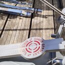 Detailní pohled na šedý bicí pedál z kovu. Na stupni je červený nápis „SONOR GERMANY SINCE 1875“ a kruhové logo. V pozadí je vidět chromovaný stojan…