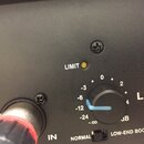 Detailní záběr na černý ovládací panel elektronického zařízení. Je zde vidět otočný knoflík s modrým ukazatelem, nápis LIMIT u žluté kontrolky a stup…