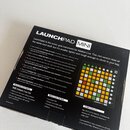 Krabice s nápisem LAUNCHPAD MINI, která obsahuje MIDI kontrolér v černé barvě s mřížkou barevných podsvícených políček. Na spodní části je viditelné…