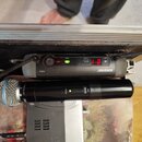 Černý bezdrátový mikrofon s nápisem BETA 58A a PGX2. Nad ním je umístěn šedý vysílač s logem SHURE a označením PGX4, který má zapnuté červené a zelen…