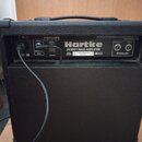 Zadní strana černého basového komba s texturovaným povrchem. Na zadním panelu je bílý nápis Hartke, 20 WATT BASS AMPLIFIER a model B200. Jsou zde vid…