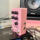 Růžový efekt pedál s nápisy DELAY, D7 a X2. Na horní části jsou čtyři černé ovládací knoflíky s popisky TWEAK.1, MIX, TWEAK.2 a TIME, dále jeden knof…