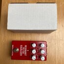 Červený kytarový efekt s nápisy BROUGHTON a RESONANT FILTER EQUALIZER. Zařízení má tři bílé otočné knoflíky s popisky HIGH PASS (80, 25), MID EQ (200…