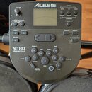 Černý elektronický modul Alesis NITRO. Na horní části je displej, ovládací knoflík VOLUME a několik tlačítek s nápisy NORMAL, SONG, KIT, VOICE, PATTE…