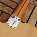 Detail spojení krku a těla elektrické kytary v natürliche dřevěné barvě. Na kovové krytce spojovacího spoje je nápis „Fender Custom Shop Designed in…