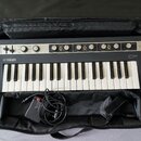 Klávesový nástroj Yamaha CP v černé barvě s bílými klávesami, umístěný v černém polstrovaném pouzdře. Na horním ovládacím panelu jsou nápisy YAMAHA,…