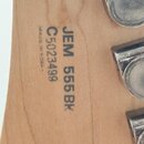 Detail zadní strany hlavy kytary zC světlého dřeva. Je zde vyryto označení JEM 555 BK, sériové číslo C5023499 a nápis MADE IN KOREA. V pravé části js…