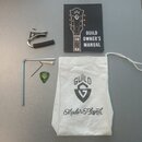 Na šedém povrchu je rozložen příslušenství k nástroji. Sada obsahuje bílý plátěný vak s nápisy GUILD, logem ve tvaru štítu a textem Made To Be Played…