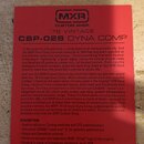 Fotografie zachycuje červený papírový leták s textem. V horní části je logo MXR a nápisy CUSTOM SHOP, '76 VINTAGE a CSP-028 DYNA COMP. Text pod nimi…