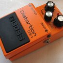 Oranžový efekt pedál s černým spínacím tlačítkem, na kterém je vyražen nápis BOSS. Na horní části jsou nápisy Distortion a DS-1, dále označení OUTPUT…