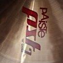 Detailní záběr na kovový činel s viditelnou strukturou broušení povrchu. Na čineli je červené logo Paiste a nápis PST, pod kterým je uveden text 18"…