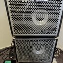 Dvě černé basové reprobedny značky Hartke naskládané na sebe. Obě mají kovovou perforovanou mřížku a nápis HyDrive v pravém dolním rohu, horní bedna…