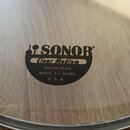 Průhledný buben s černým logem a nápisy. Na středovém štítku je uveden název SONOR, model Clear Medium a text DRUM HEAD MADE BY REMO U. S. A. Povrch…