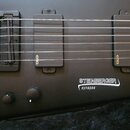 Detail černého těla elektrické basy s nápisy STEINBERGER a synapse. Nástroj je vybaven dvěma černými snímači s logem EMG a černým mostem s nápisy STE…